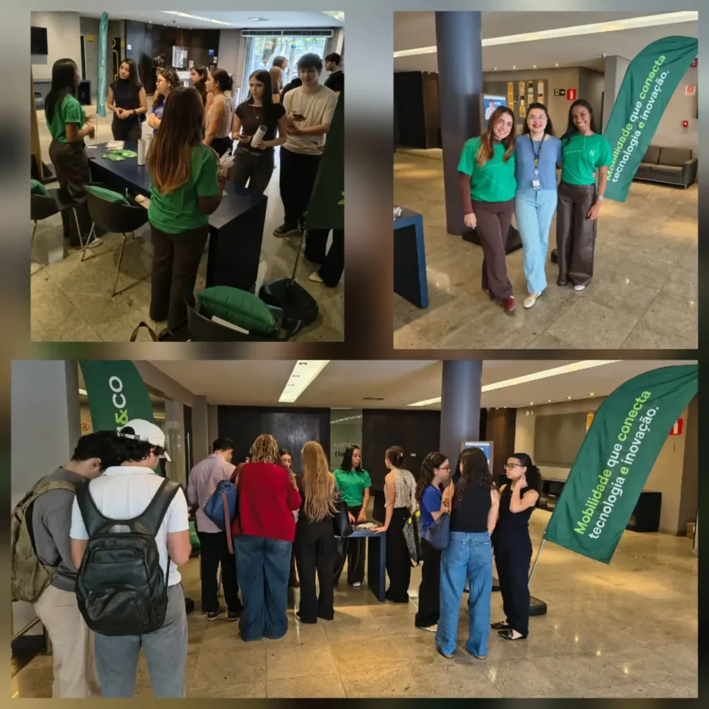 Equipe em evento técnico em ambiente corporativo, com participantes usando camisetas verdes e crachás, conversa em círculo e banner verde com frase sobre tecnologia.